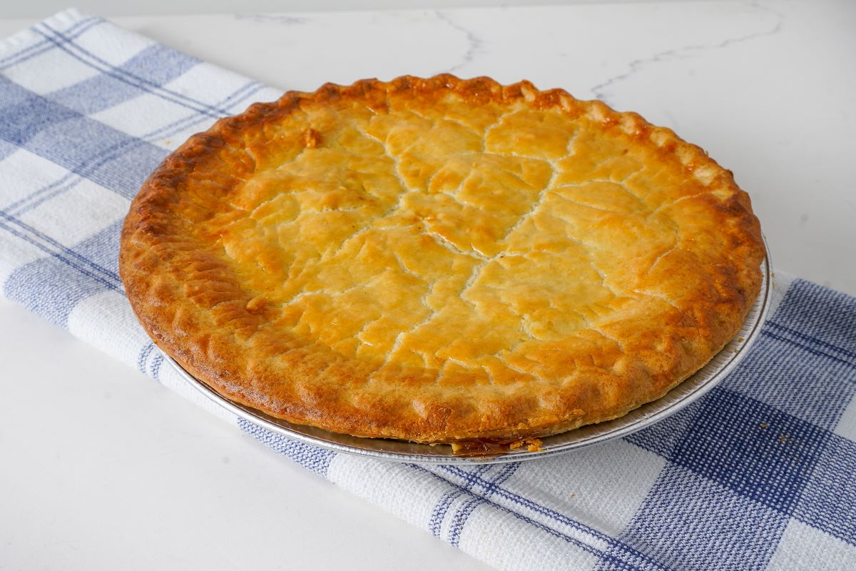 Polly's Pies Chicken Pie sitting on a blue and white linen on top of a marble table.