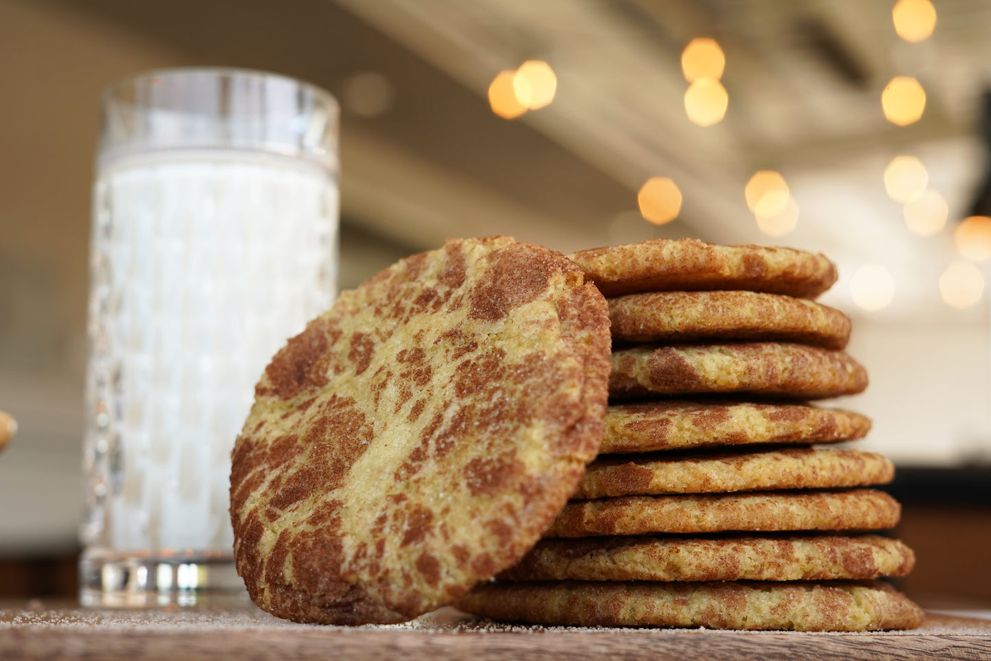 Nine Polly's Pies Snickerdoodle. cookies stacked on top of each other with a glass of milk in the background.