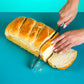 Polly's Pies loaf of Sourdough Bread on top of  a blue background. A hand  with pink nail polish is slicing the loaf with a bread knife.