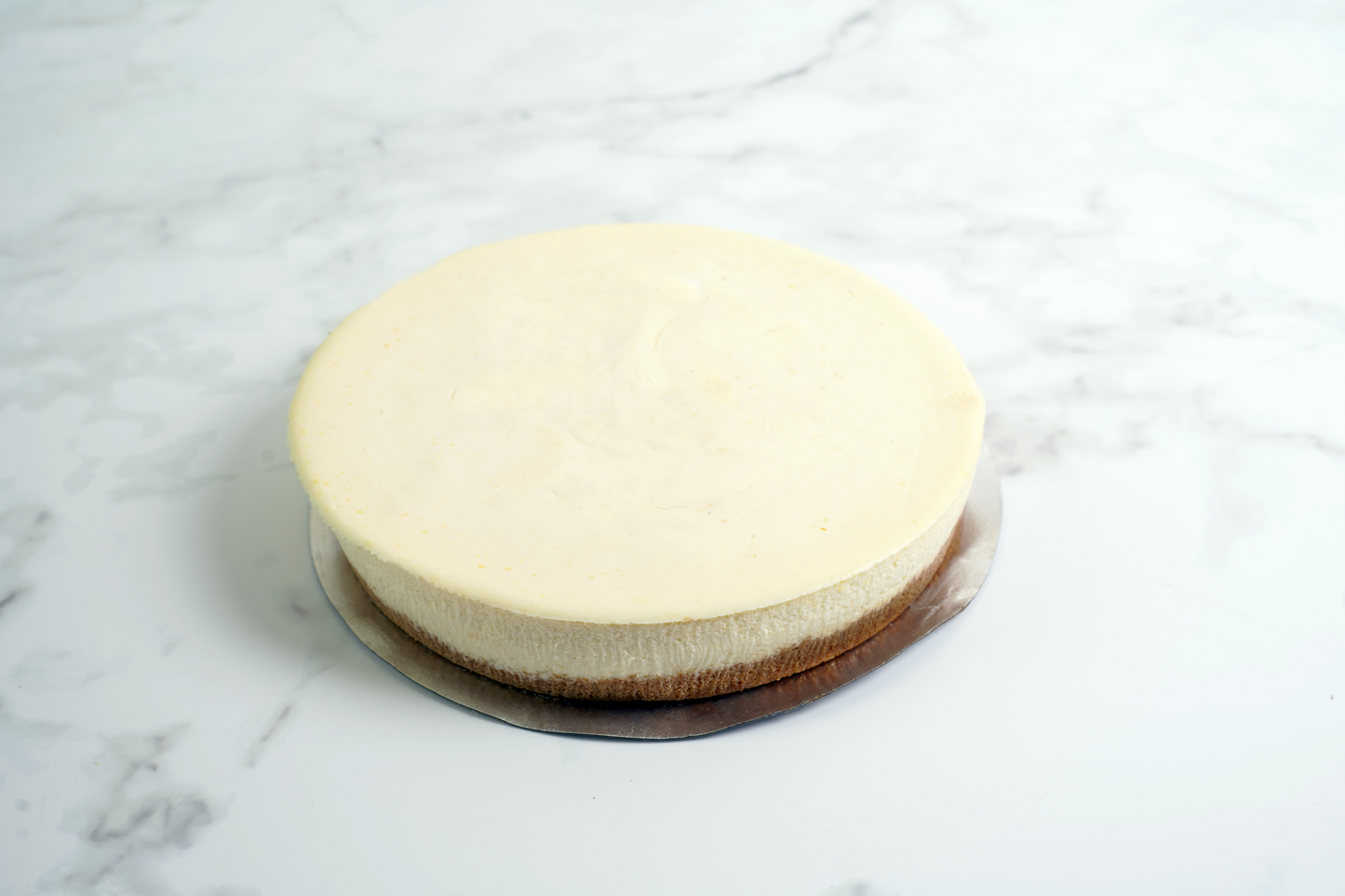 Polly's Pies traditional Cheesecake sitting on a marble countertop. 